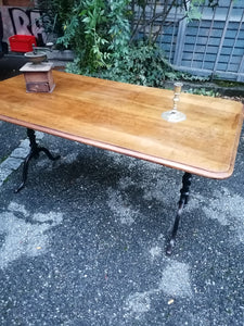 Table de bistrot ancienne, plateau en noyer massif. Pieds en fonte. Bords arrondis.
