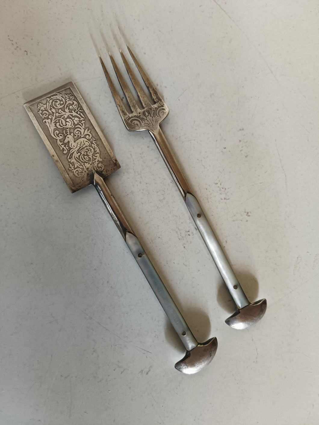 Object mystérieux, probablement une paire de service à sardine .. ça y ressemble .. acier gravé à l'acide et manche nacre