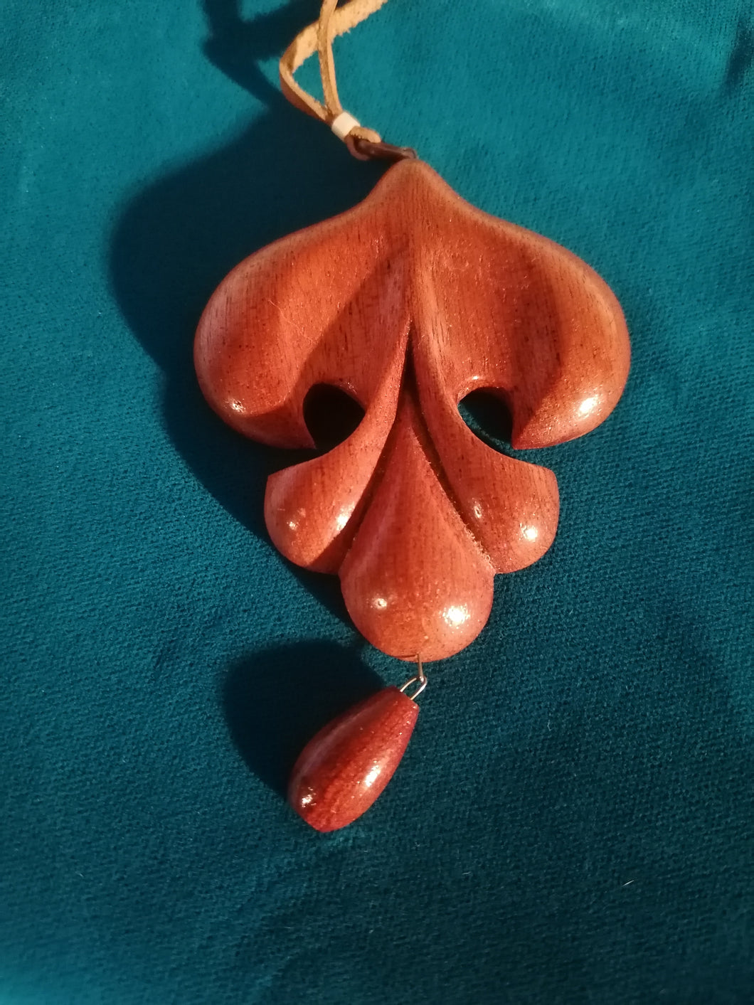 Pendentif en bois exotique sculpté, collier en cuir. 